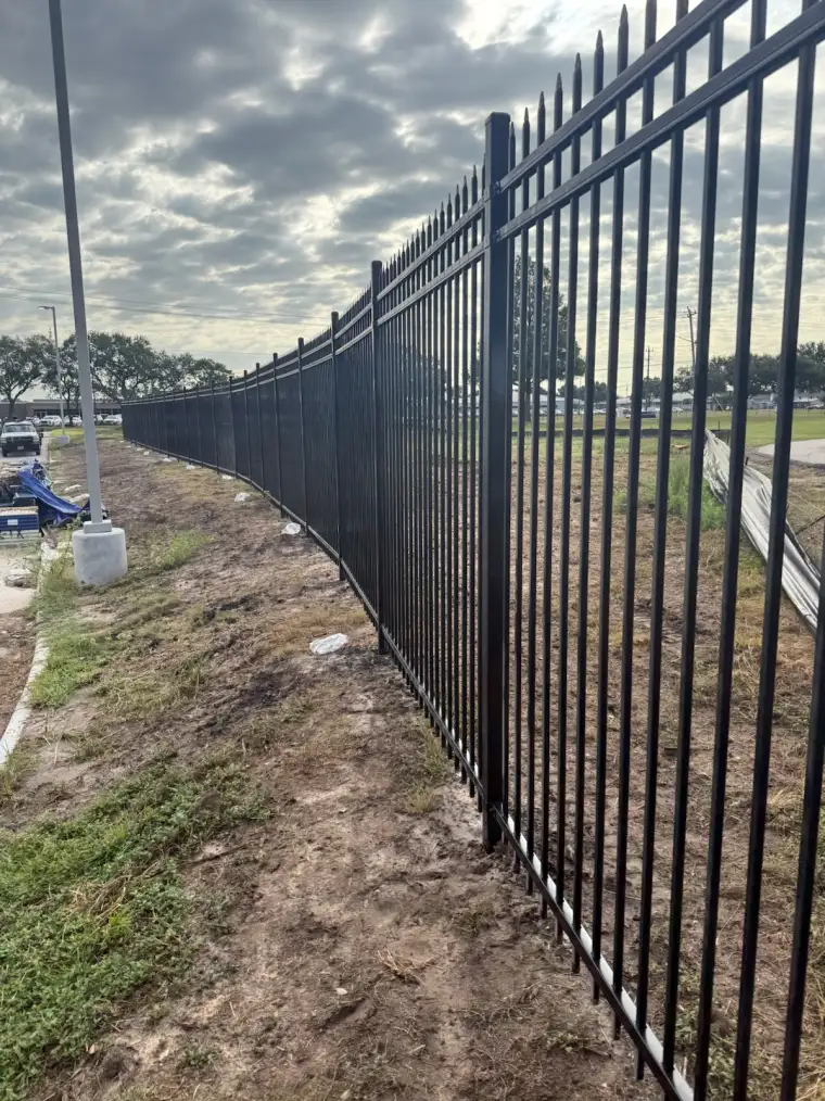 Long curving run of black ornamental iron perimeter fence built by Pasadena Fence Co. in Pasadena, Texas